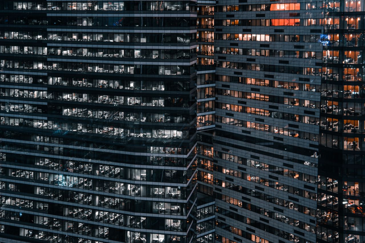 Modern office towers lit up at night.