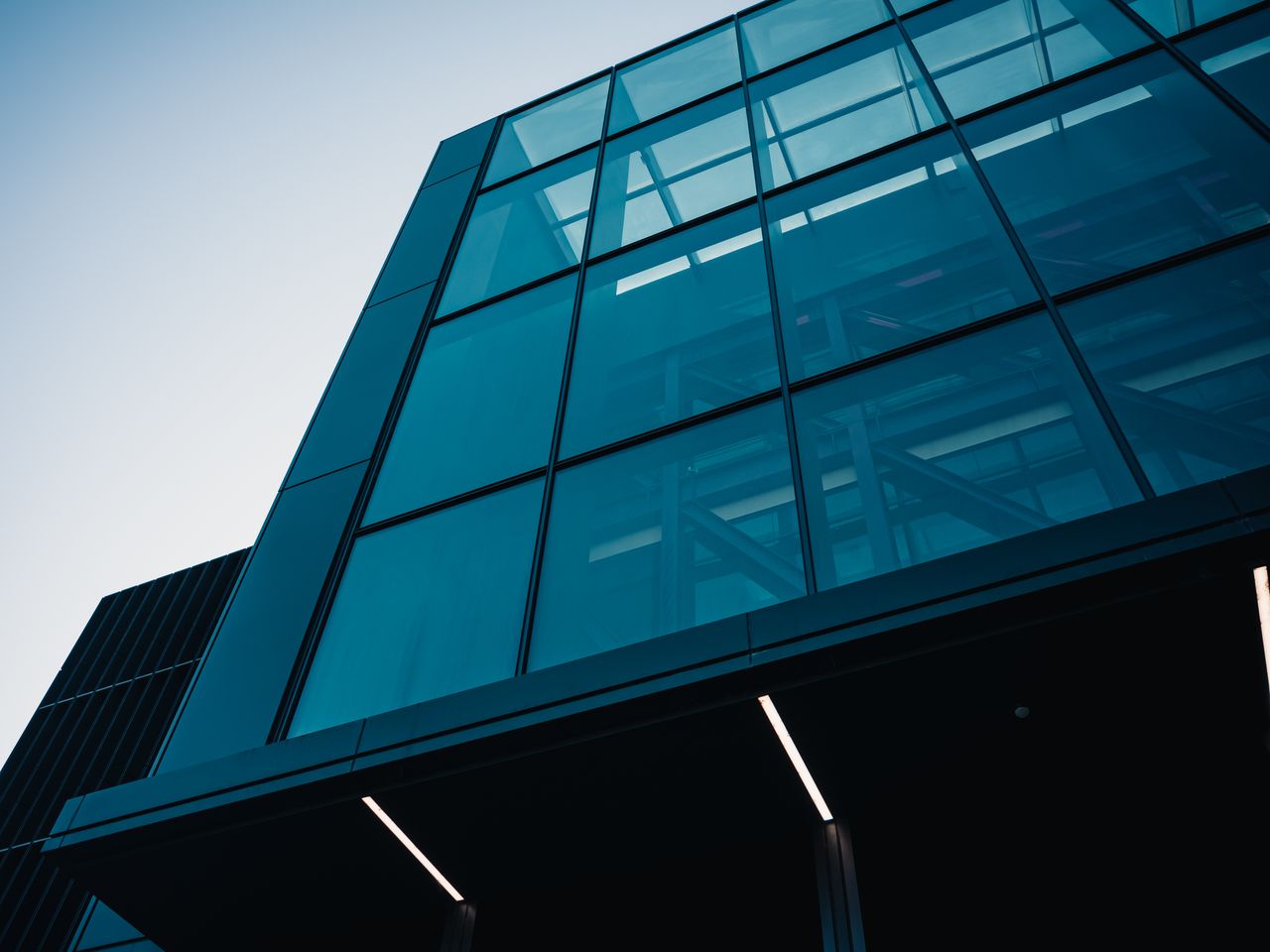 A modern glass office building viewed from a low angle.