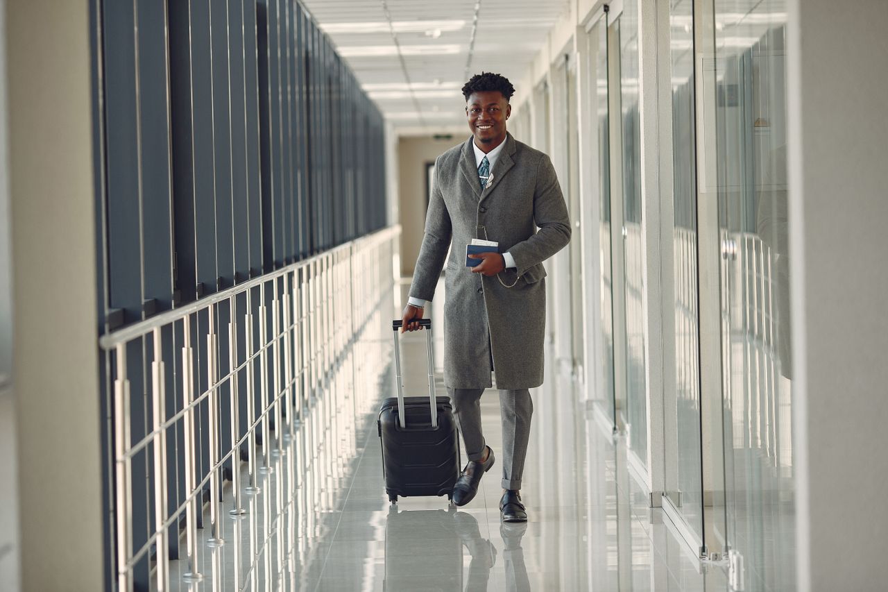 A man walking through a glass corridor carrying a suitcase.