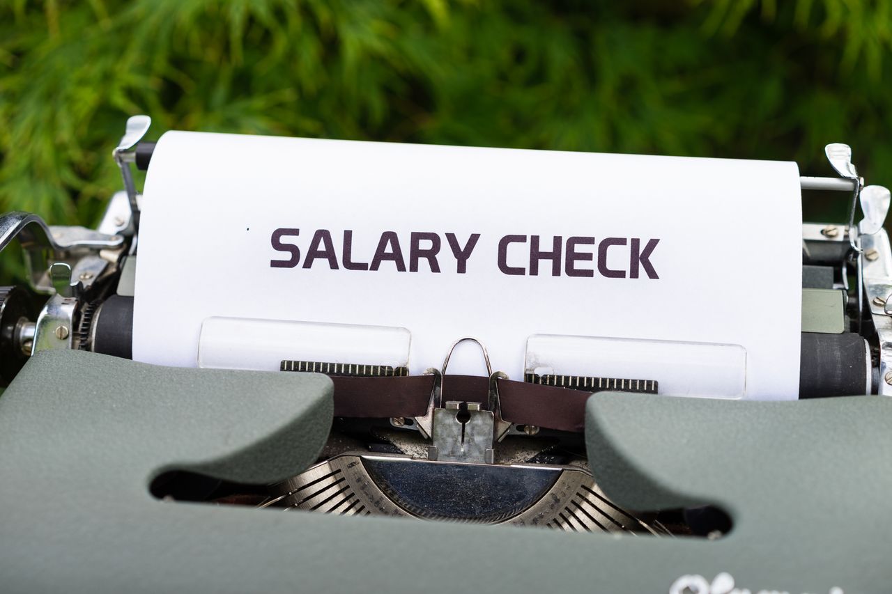 Close-up of a vintage typewriter typing 'Salary Check' on paper, symbolising payroll and finance.