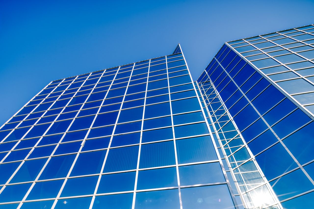 A modern glass office tower seen from below.