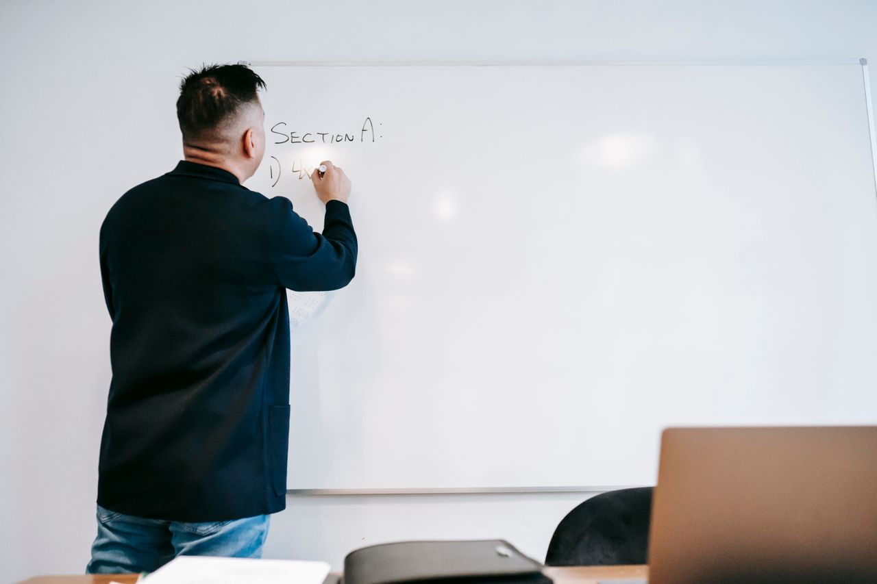 An instructor writing 'Section A' on a whiteboard.