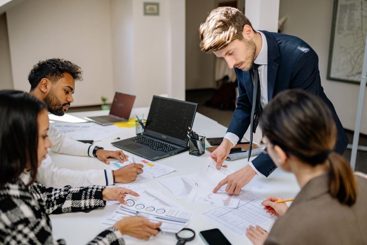 A team reviewing printed financial charts, one person pointing.