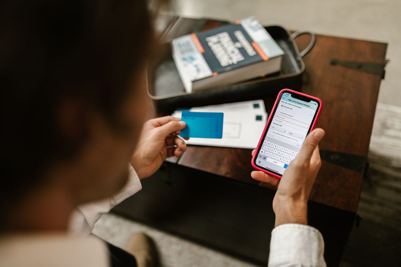 A person holding a payment card while entering details on a phone.