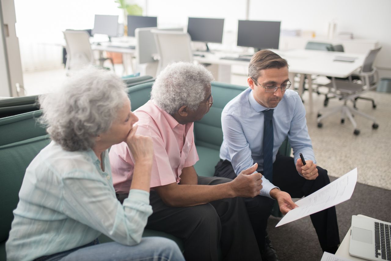 A younger adviser showing a document to an elderly couple.