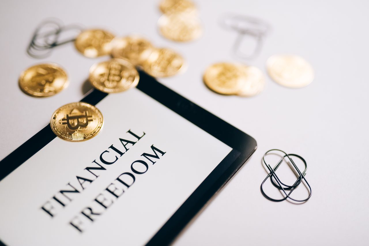 Close-up of Bitcoin coins and an iPad displaying 'Financial Freedom,' symbolising modern digital savings.